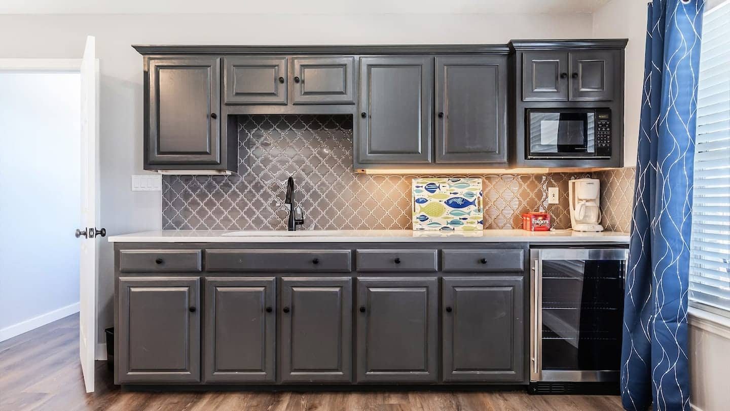 Kitchenette with grey cabinets, a sink, microwave and beverage fridge