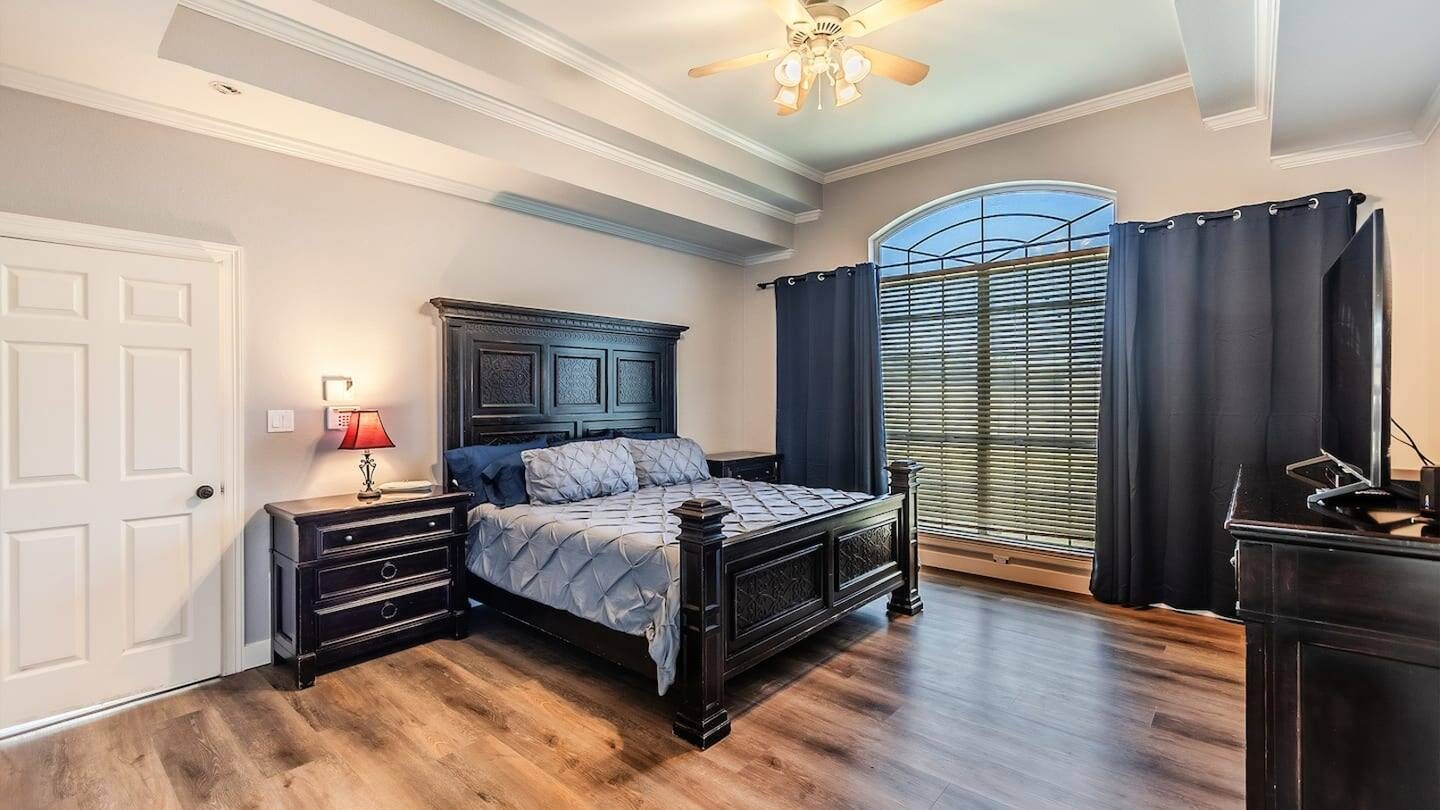 Bedroom with a dark wood king bed, nightstand lamp and vaulted ceiling