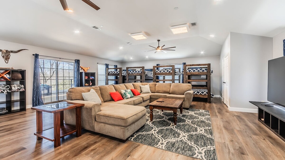Spacious upstairs guest house lounge with a sectional sofa, television and bunk beds along the back wall