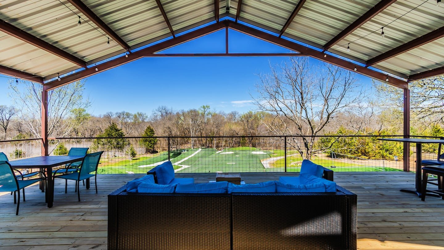 Covered pavilion with a vaulted metal roof, outdoor sofas and a view over the fields